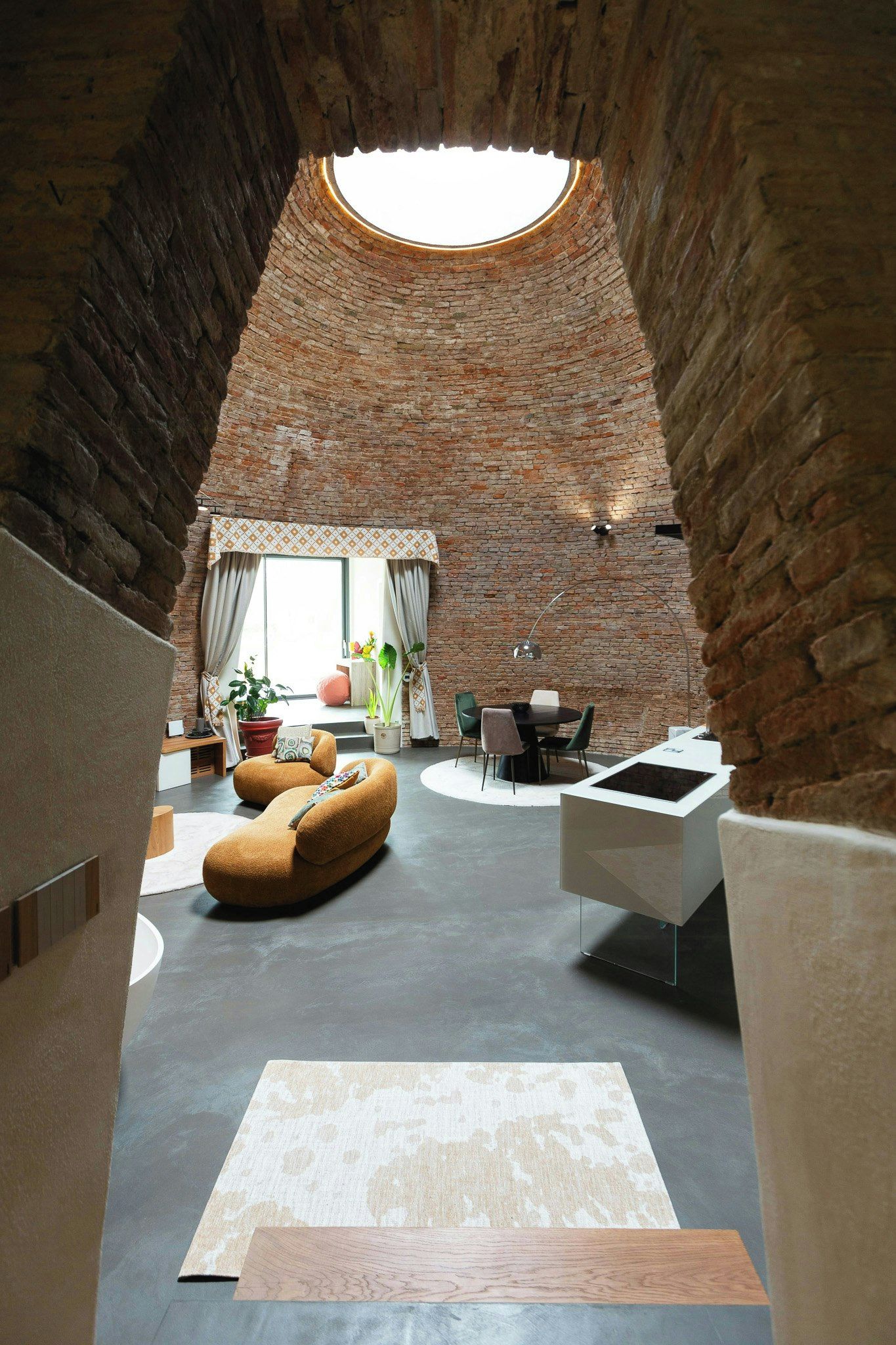 An interior with a brick ceiling, a round skylight, a dining area, and a modern seating arrangement.