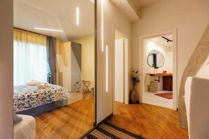 A modern bedroom with a bed, a bedside table, a mirror, and a wooden floor. - Renovated Icehouse Along Wine and Food Trails (Anzola dell'emilia)