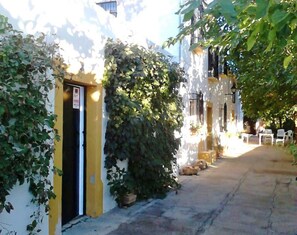 A narrow alleyway with buildings on either side, some with plants growing over them, and a few outdoor seating areas. - Farmhouse With Pool in Andalusia (Antequera)