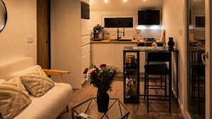 A compact living space with a kitchen, dining area, and a sofa with a coffee table. - Nid de Láir • Private retreat with a hot tub and sauna (Langeac)