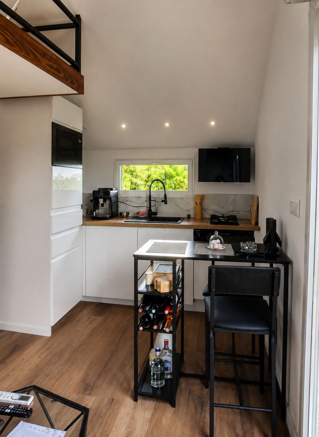 A compact kitchen with a built-in microwave, a coffee machine, and a window with a view of greenery.