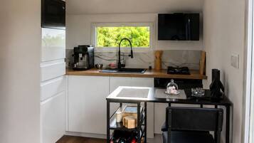 A compact kitchen with a built-in microwave, a coffee machine, and a window with a view of greenery.