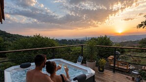 A hot tub on a wooden deck with a view of the sunset over a forested landscape. - Nid de Láir • Private retreat with a hot tub and sauna (Langeac)