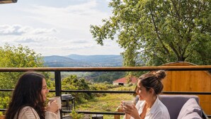 Two individuals seated at an outdoor table with a view of a landscape. - Nid de Láir • Private retreat with a hot tub and sauna (Langeac)