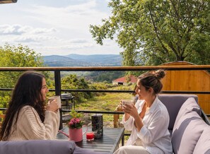 Two individuals seated at an outdoor table with a view of a landscape.