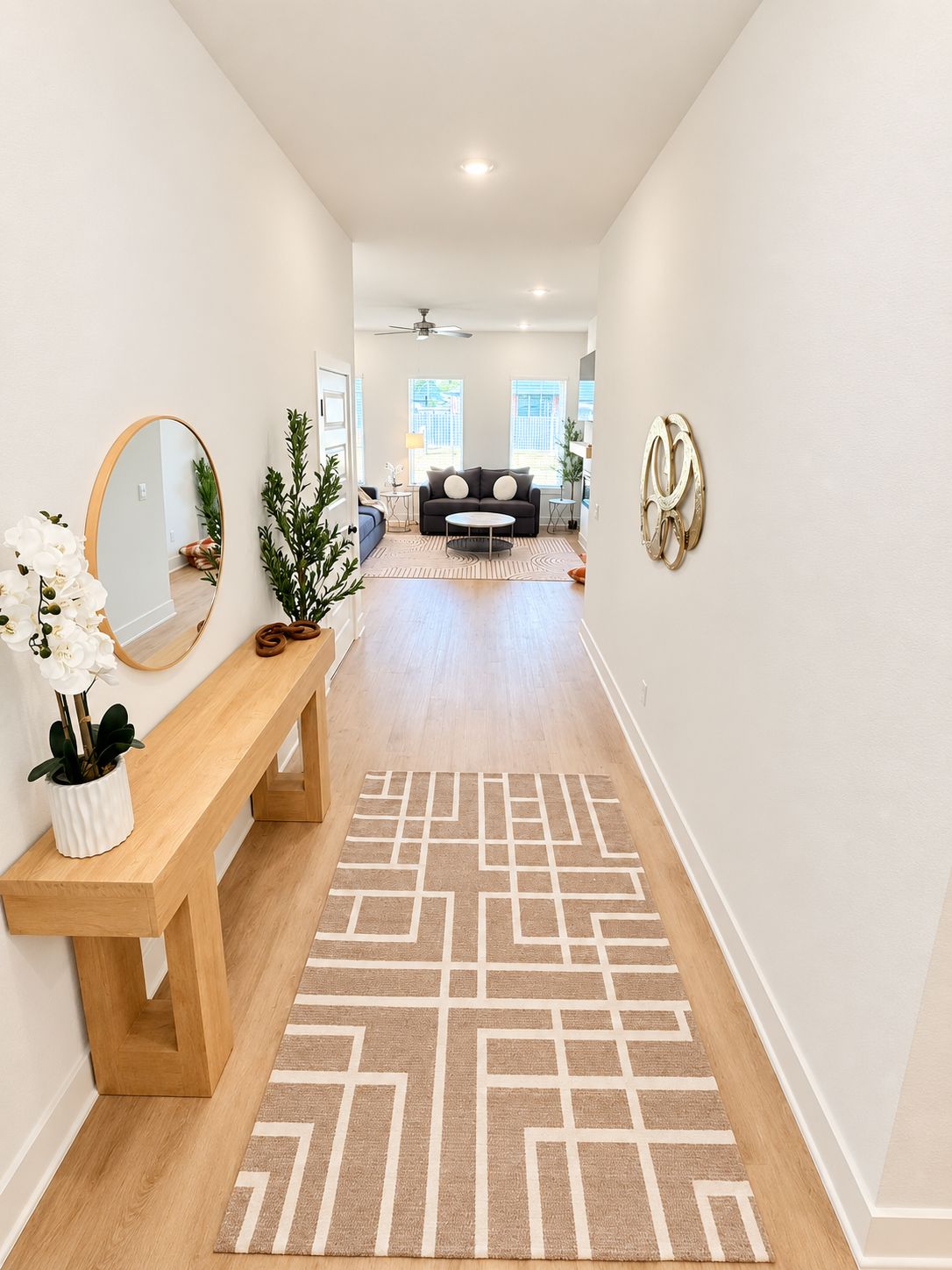 A hallway with a wooden bench, a patterned rug, a mirror, and a plant.