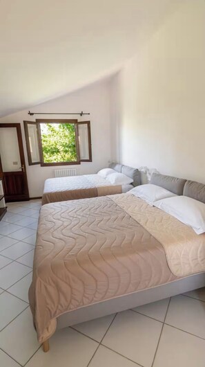 A bedroom with two beds, a window, and a radiator.