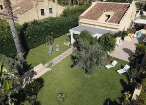 A courtyard with a covered seating area, a lawn, and surrounding greenery.