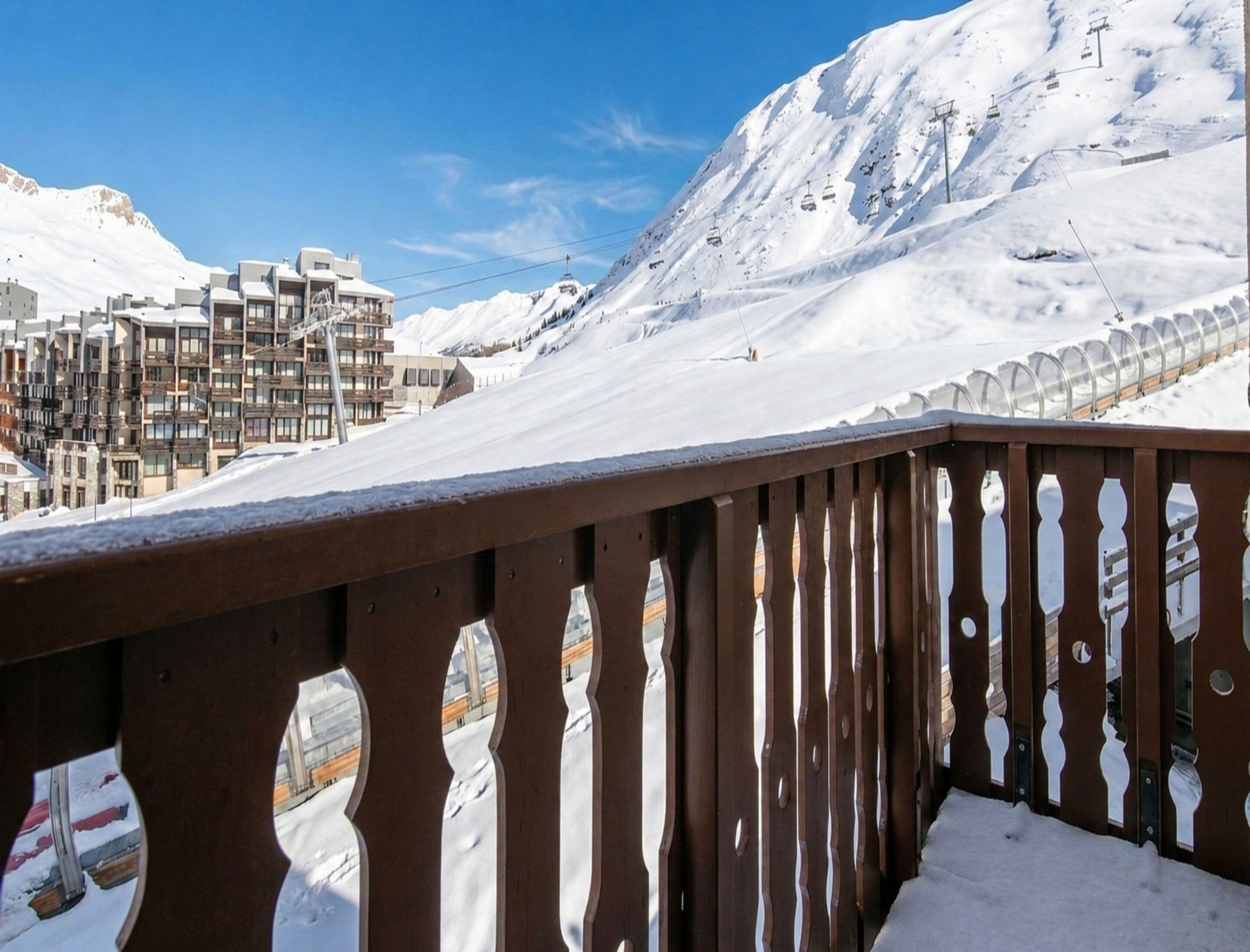 A snow-covered mountain with a ski lift and buildings in the background.
