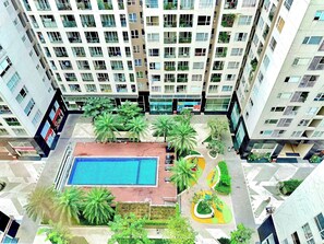 A high-rise residential building with multiple balconies, a central courtyard with a swimming pool, and surrounding greenery. - AYA LUXURY APARTMENT (ho chi minh)