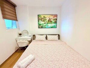 A bedroom with a bed, a desk with a mirror, a window with blinds, and a painting on the wall. - AYA LUXURY APARTMENT (ho chi minh)