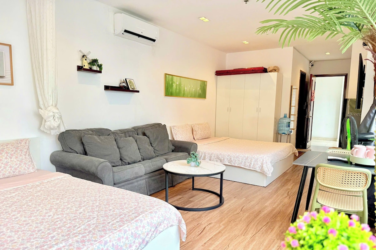 Ein Zimmer mit einer Couch, zwei Einzelbetten, einem kleinen Tisch, einem Kleiderschrank und einem Ventilator.