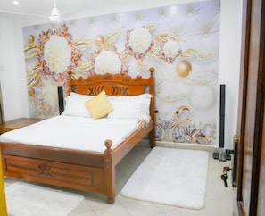 A bedroom with a wooden bed, white bedding, and a decorative wall mural. - Sunny Yellow cozy Apartment (Mombasa)