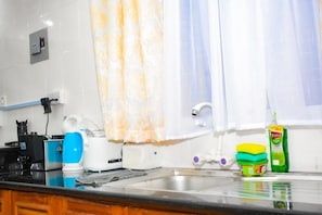 A kitchen with a sink, a coffee maker, a toaster, and a bottle of dish soap. - Sunny Yellow cozy Apartment (Mombasa)