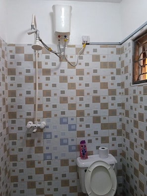A small bathroom with a toilet, a shower, and a wall-mounted toilet paper holder. - Sunny Yellow cozy Apartment (Mombasa)