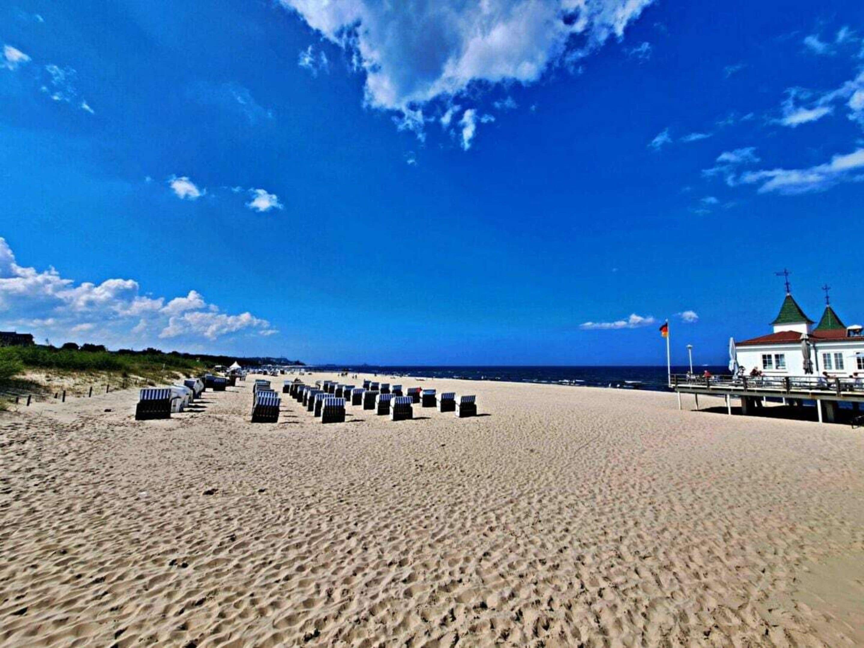 Una playa con una fila de sillas y un edificio de techo verde.