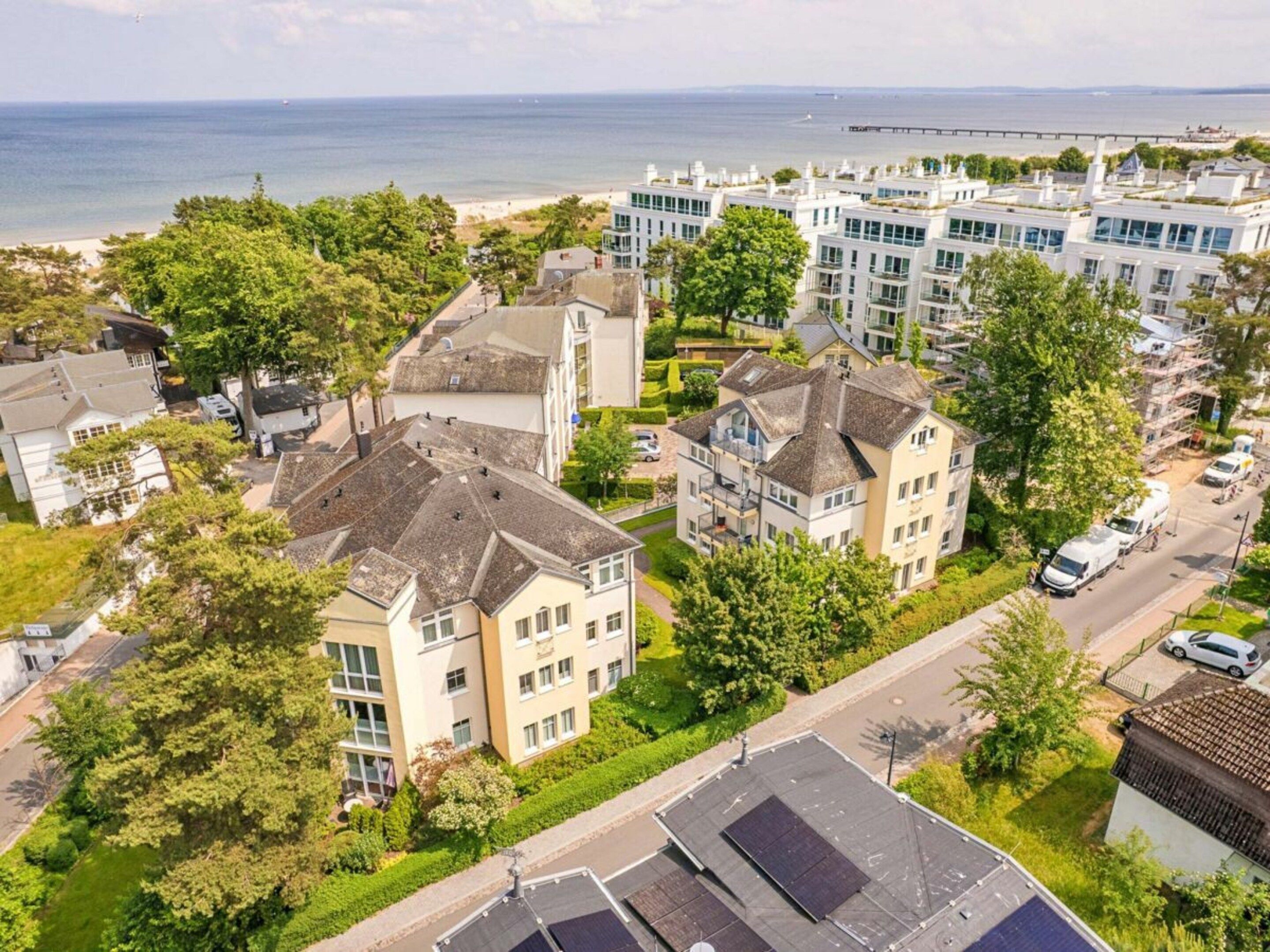 A residential area with houses, a road, and a view of the sea.