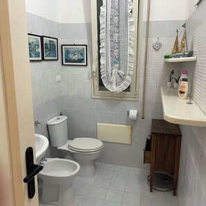A bathroom with a toilet, bidet, and sink. There are framed pictures on the wall and a shower curtain. - Villa La Pineta. Equipped with every comfort. Located in the marine protected area (Sicilia)