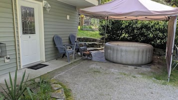 A covered patio area with outdoor furniture, a fire pit, and a large round seating area.