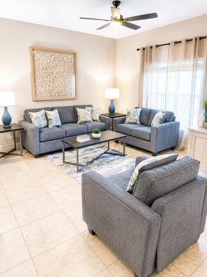 A living room with two sofas, a coffee table, and a floor lamp. - Vacation in the most sought location near Disney (Kissimmee)