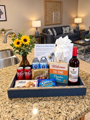 A welcome gift tray with snacks, drinks, and a bottle of wine in a hotel setting. - Vacation in the most sought location near Disney (Kissimmee)