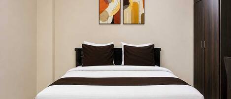 A bedroom with a bed, two pillows, a headboard, and a wardrobe.