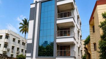 A multi-story building with a modern design, featuring a prominent glass facade and balconies on the upper floors.