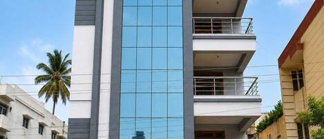 A multi-story building with a prominent glass facade, balconies, and a modern architectural design.