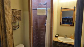 A bathroom with a shower, toilet, sink, and a mirror.