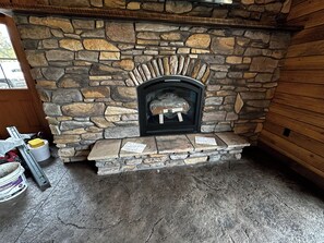 A stone fireplace with a metal screen, a wooden door, and a bucket with a yellow sponge.