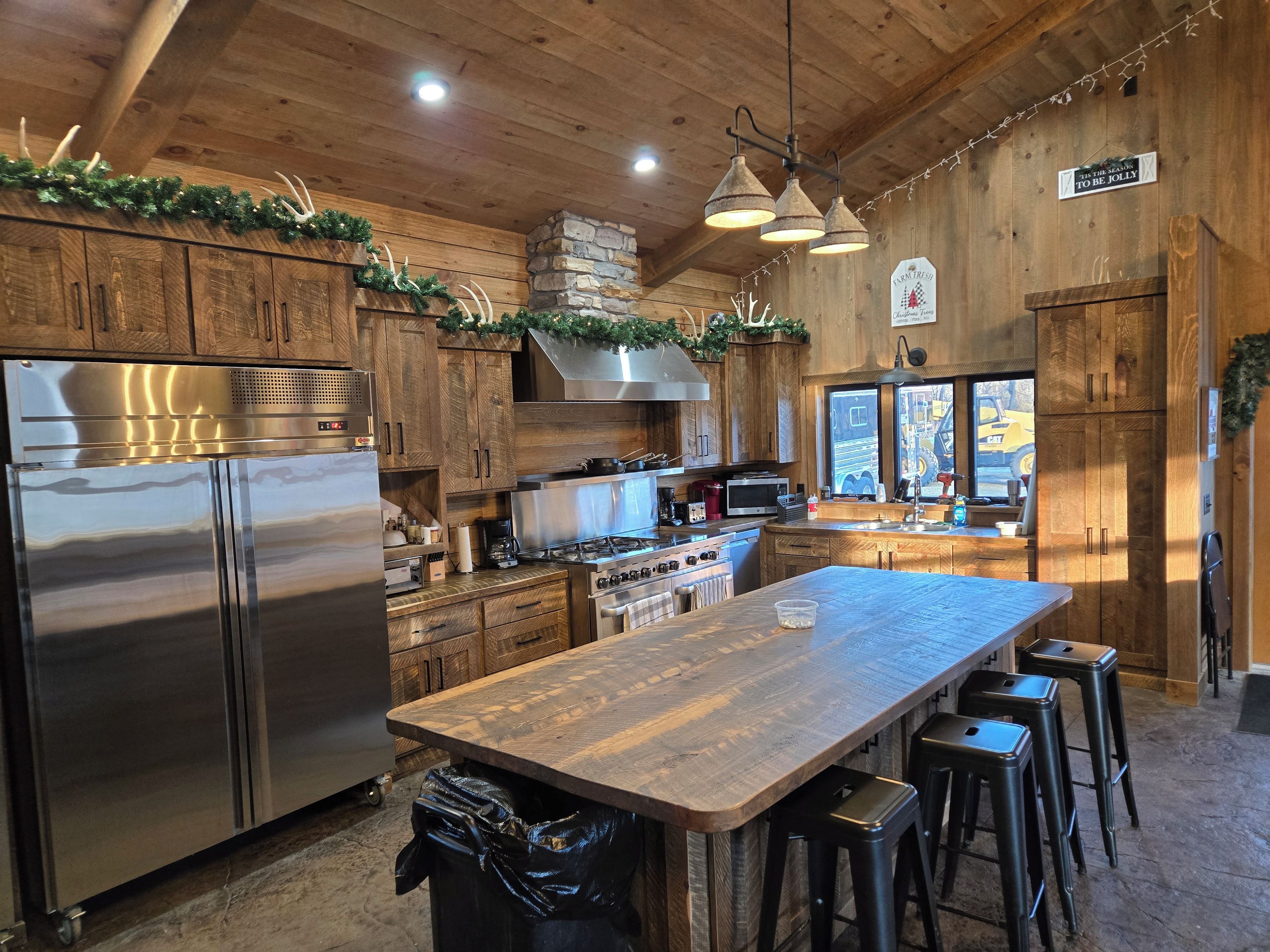 Une cuisine moderne avec des meubles en bois, des appareils électroménagers en acier inoxydable et un îlot central doté de tabourets de bar.