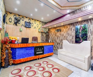 Ein Empfangsbereich mit einer Rezeption, einer Uhr, einer Couch und einer Wand mit Musterdesign.