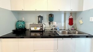 Een keuken met witte kasten, een zwart aanrecht, een broodrooster, een waterkoker en een spoelbak.