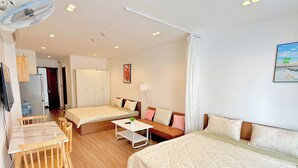 Een hotelkamer met een bed, een bank, een bureau met stoelen, een ventilator en een schilderij aan de muur.