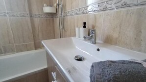A bathroom with a white sink, a towel, and a shower.