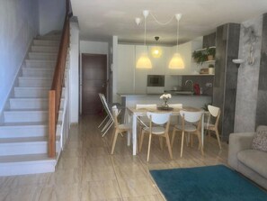 A modern living space with a staircase, dining area, kitchen, and a sofa.