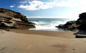 A beach with rocky cliffs and a sandy shore.