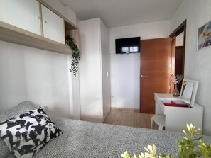 Une chambre à coucher de taille réduite, comprenant un lit, un bureau et une armoire.