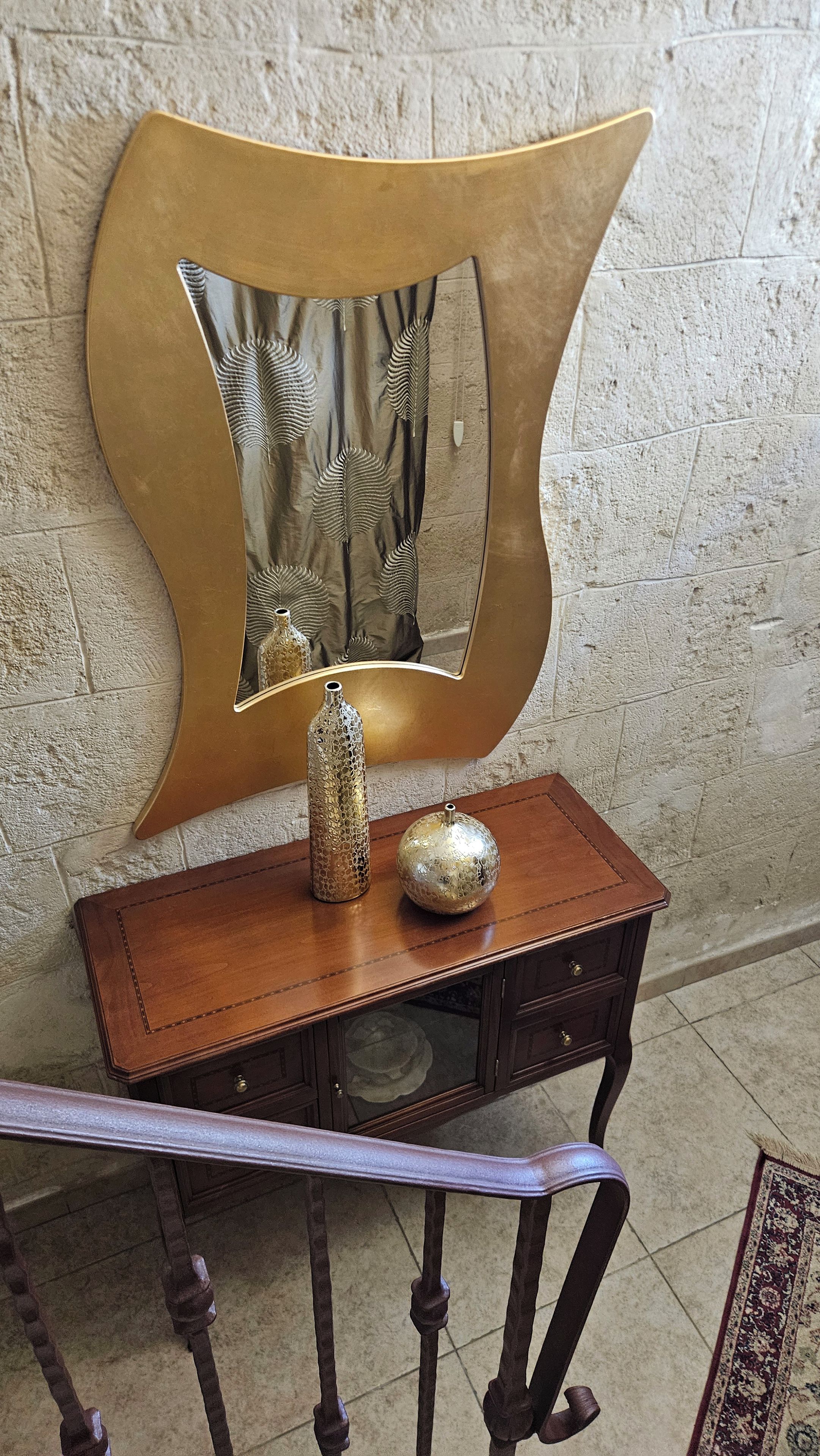 A wooden console table with two decorative vases and a mirror with a gold frame.