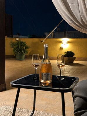 A bottle of Maschio Prosecco wine, two wine glasses, and a small table on an outdoor patio at night. - Just a few minutes from Bari—the perfect starting point for experiencing Puglia at its best (Capurso)
