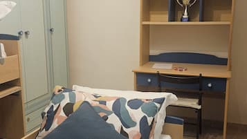 A bedroom with a bed, a desk, a wardrobe, and a trophy on the desk.