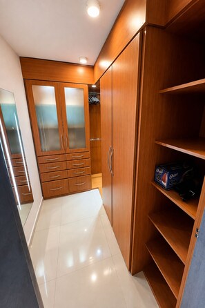 A walk-in closet with wooden cabinets, a mirrored closet door, and a shelf with a box. - Hermosa Casa Familiar en Cabudare, Terraza+Wi-Fi (Cabudare)