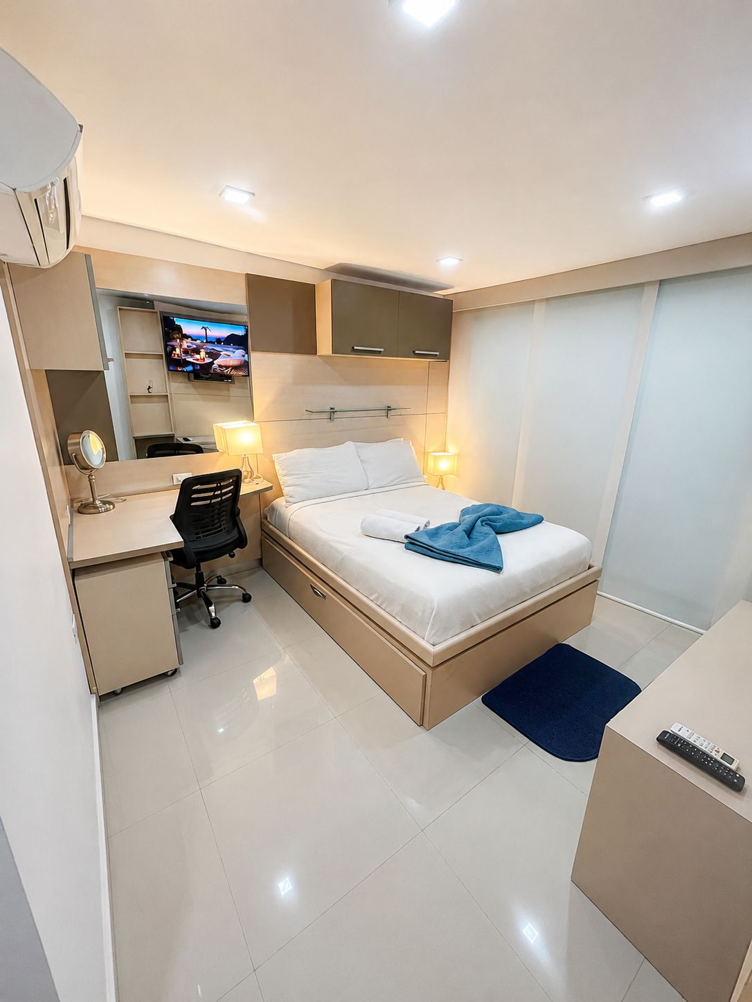 Una camera d'albergo con un letto, una scrivania, una sedia e un televisore a parete.