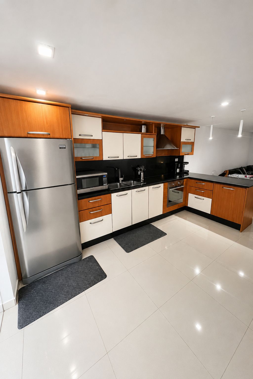 A modern kitchen with stainless steel appliances, wooden cabinets, and a black countertop.