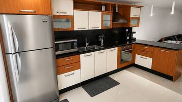 A modern kitchen with stainless steel appliances, wooden cabinets, and a black countertop.