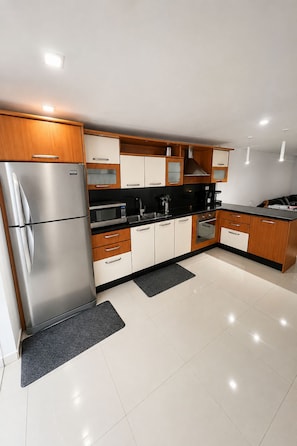 A modern kitchen with stainless steel appliances, wooden cabinets, and a black countertop.