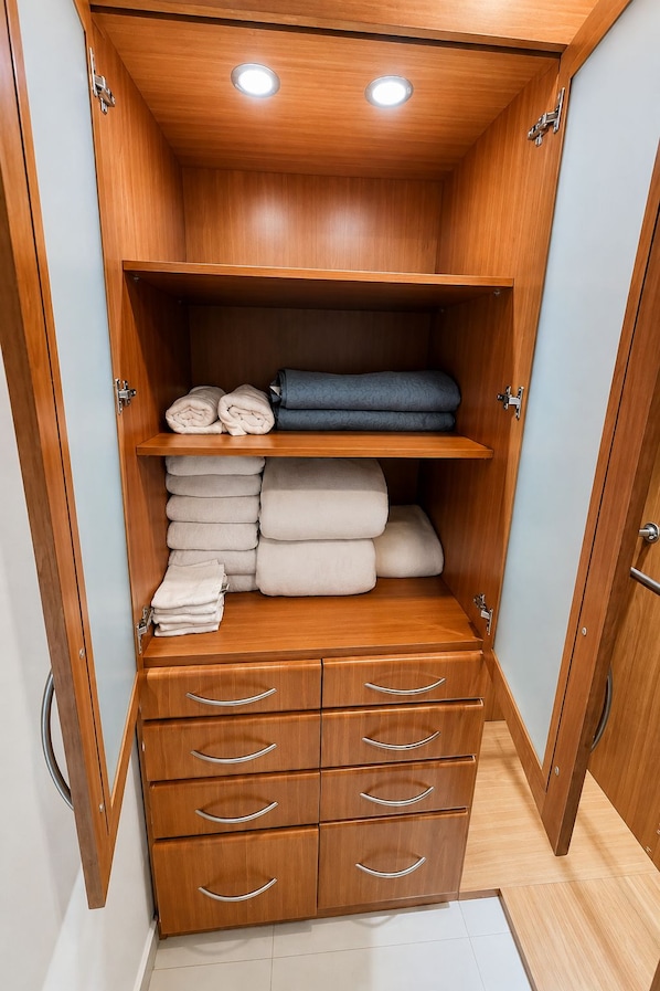 A wooden wardrobe with multiple drawers and shelves, containing folded towels and a rolled-up item.