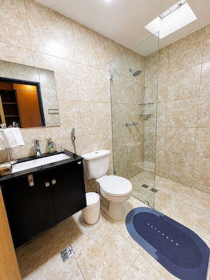 Ein modernes Badezimmer mit einer gläsernen Duschkabine, einem schwarzen Waschtisch und einer weißen Toilette.