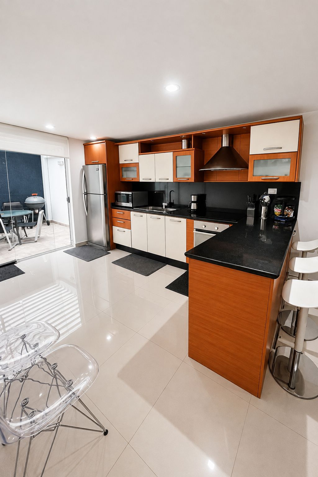 A modern kitchen with a central island, wooden cabinets, and a stainless steel refrigerator.
