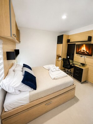 Ein modernes Schlafzimmer mit Bett, Nachttischen, einem Schreibtisch und einem Kamin.